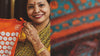 A woman holds up the Shakti Mat next to a typical Indian motif.