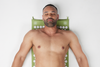 A man relaxes on a pastel green Shakti Mat with the original intensity level.